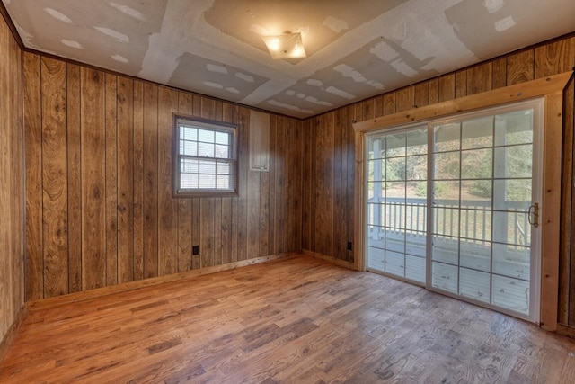 unfurnished room featuring baseboards, wood walls, and wood finished floors