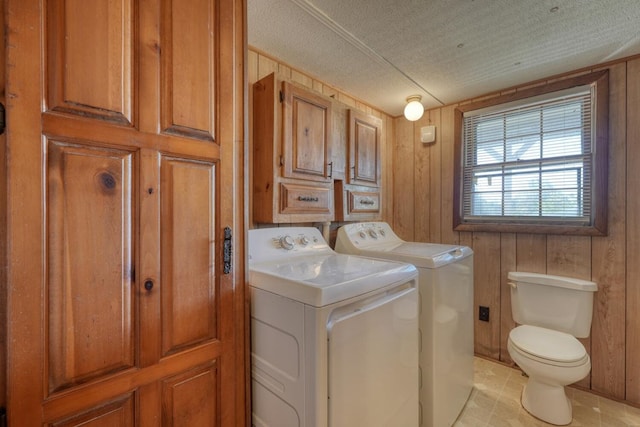 laundry room with washer and dryer, a textured ceiling, laundry area, and wooden walls