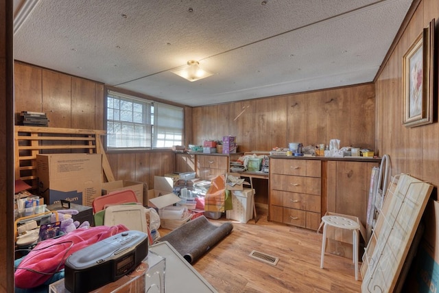 interior space with visible vents, a textured ceiling, wood finished floors, and wooden walls