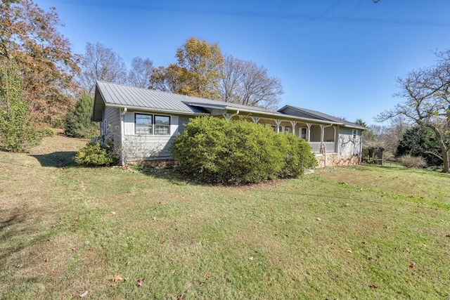 rear view of house featuring a yard and metal roof