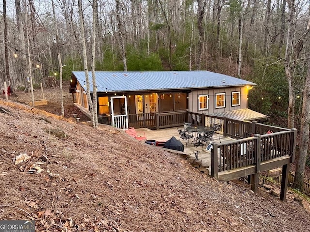 exterior space featuring board and batten siding, a forest view, and metal roof