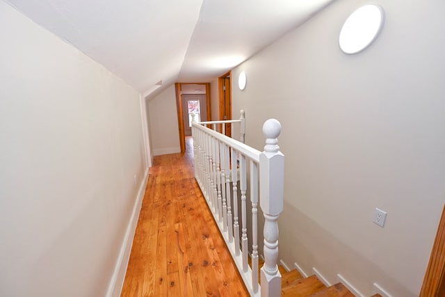 corridor with light hardwood / wood-style flooring and lofted ceiling