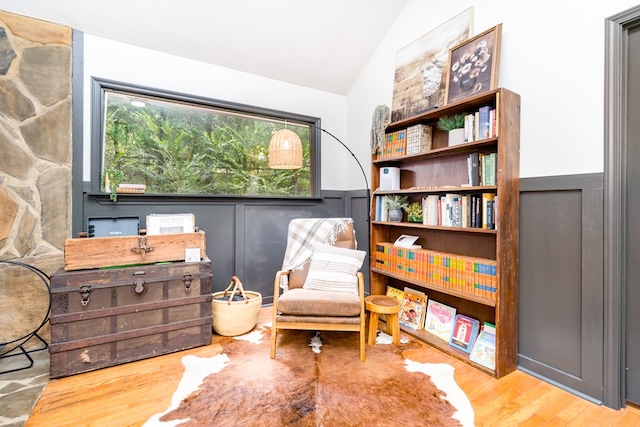 living area featuring a wainscoted wall, plenty of natural light, lofted ceiling, and wood finished floors