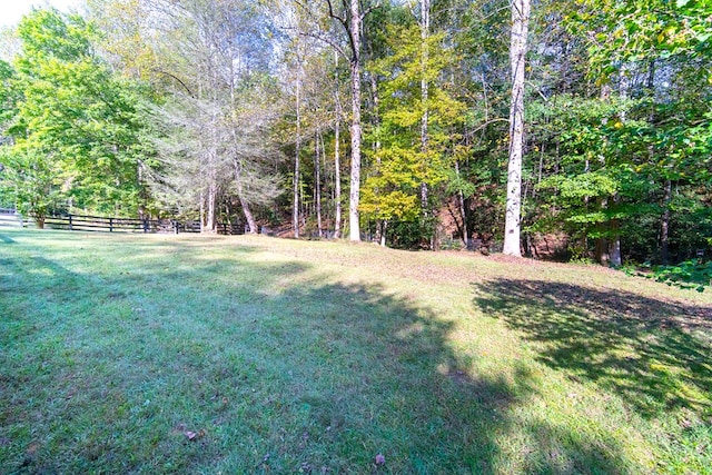 view of yard with a forest view and fence