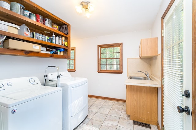 clothes washing area featuring visible vents, baseboards, cabinet space, a sink, and washing machine and dryer