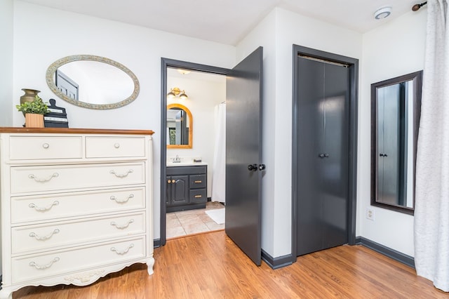 hallway with a sink, baseboards, and light wood-style floors