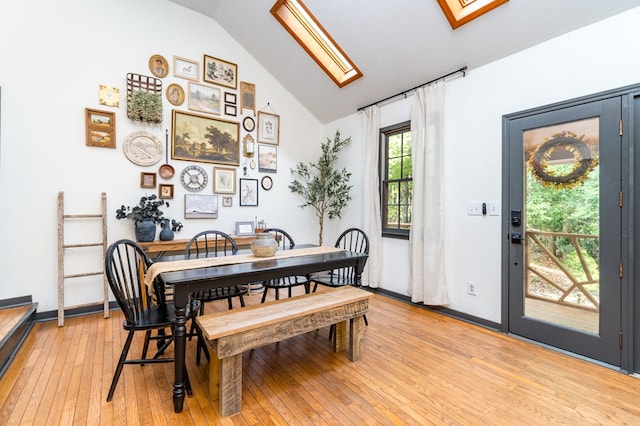 dining space featuring vaulted ceiling, light wood-style flooring, and baseboards