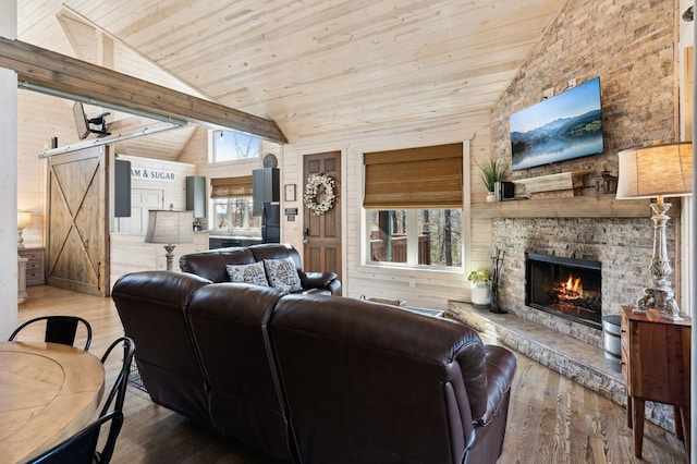 living room featuring a wealth of natural light, lofted ceiling, a barn door, and wood-type flooring