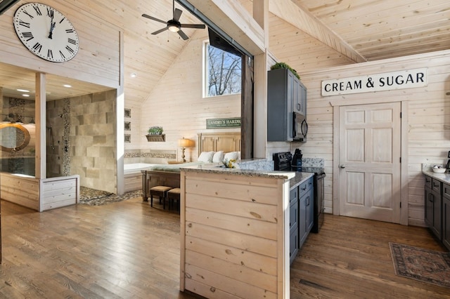 kitchen featuring dark wood-type flooring, high vaulted ceiling, wooden walls, and black appliances