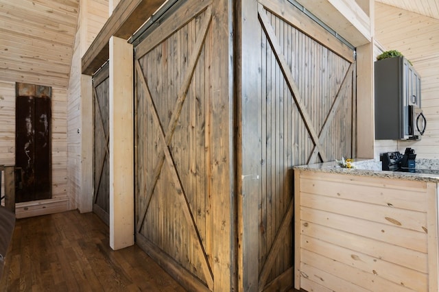 interior space with vaulted ceiling, hardwood / wood-style floors, and wooden walls