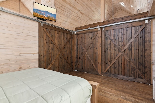 unfurnished bedroom with wooden ceiling, a barn door, wood walls, and hardwood / wood-style floors