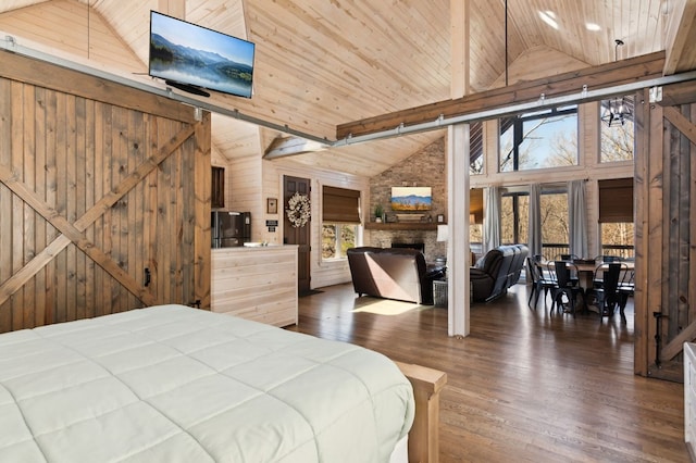 bedroom featuring a stone fireplace, high vaulted ceiling, hardwood / wood-style flooring, wooden ceiling, and a barn door