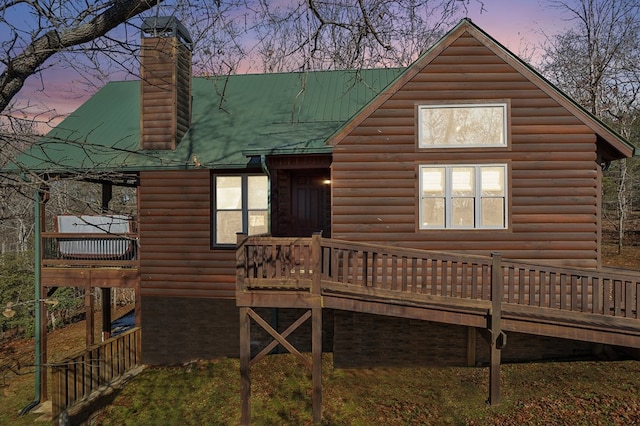 back house at dusk featuring a wooden deck