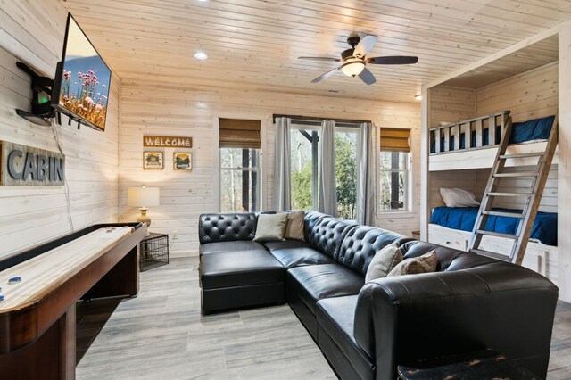 living room with ceiling fan, wooden ceiling, and wooden walls