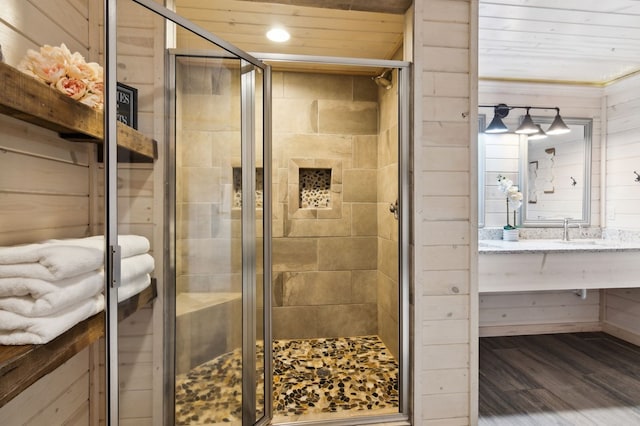 bathroom with a shower with shower door, wooden walls, and hardwood / wood-style flooring