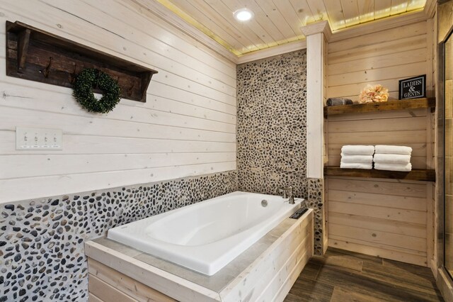 bathroom featuring wooden walls, crown molding, hardwood / wood-style floors, and a tub