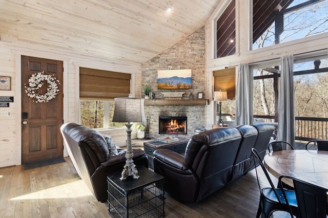 living room featuring wooden ceiling, wood-type flooring, a stone fireplace, and high vaulted ceiling