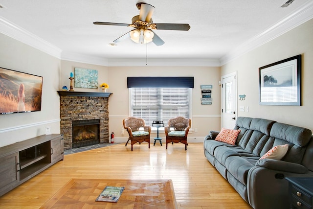 living area featuring a stone fireplace, crown molding, light wood finished floors, and ceiling fan