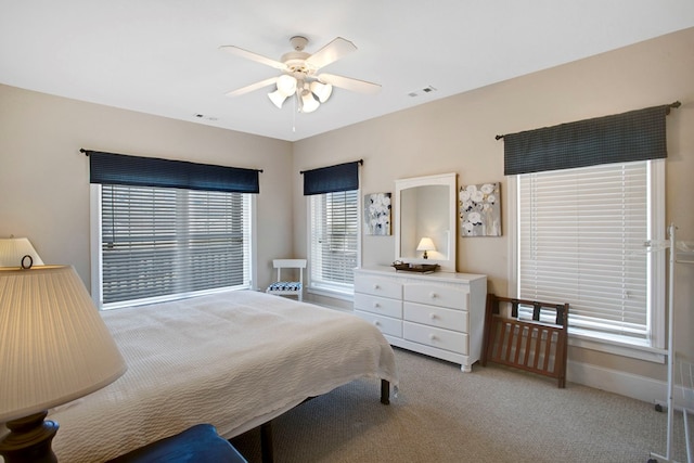 bedroom featuring a ceiling fan, light colored carpet, visible vents, and baseboards