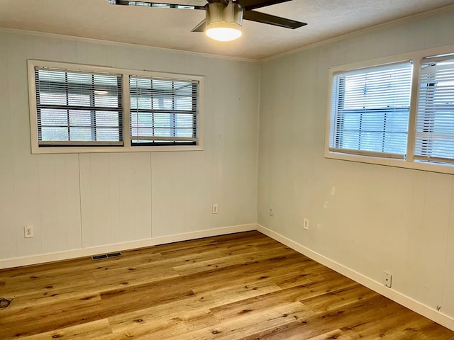 spare room featuring wooden walls, ceiling fan, hardwood / wood-style floors, and crown molding