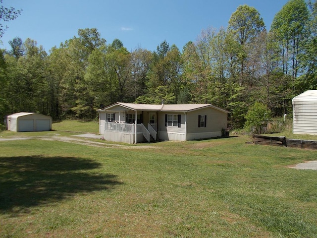 view of front facade featuring an outdoor structure, a detached garage, a front lawn, and covered porch