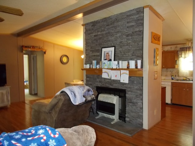 living area with a fireplace, wood finished floors, heating unit, and vaulted ceiling with beams