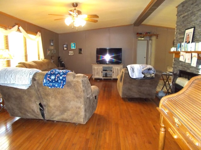 living area featuring vaulted ceiling with beams, ceiling fan, a fireplace, and wood-type flooring