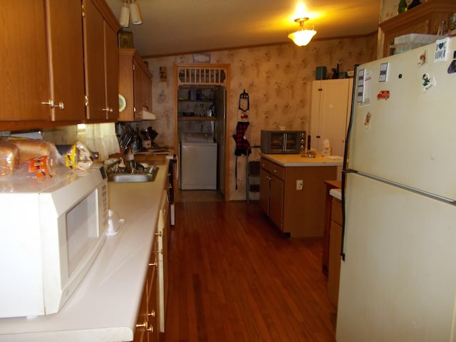 kitchen with light wood finished floors, a sink, white appliances, washer / dryer, and light countertops