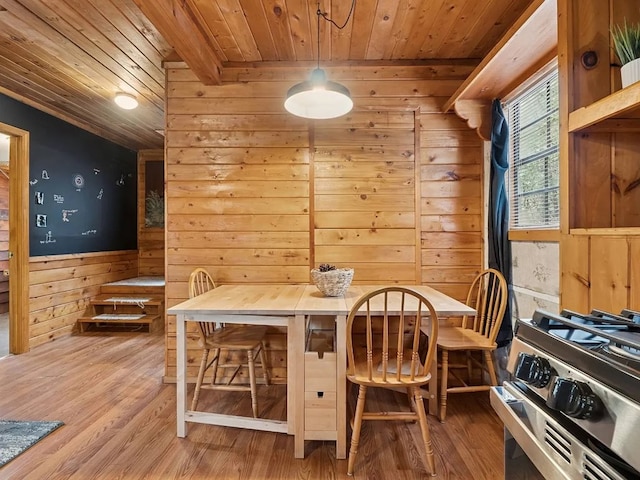 dining space featuring wood ceiling, a wainscoted wall, wood walls, and wood finished floors