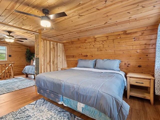 bedroom with ceiling fan, wood finished floors, wooden ceiling, lofted ceiling, and wooden walls