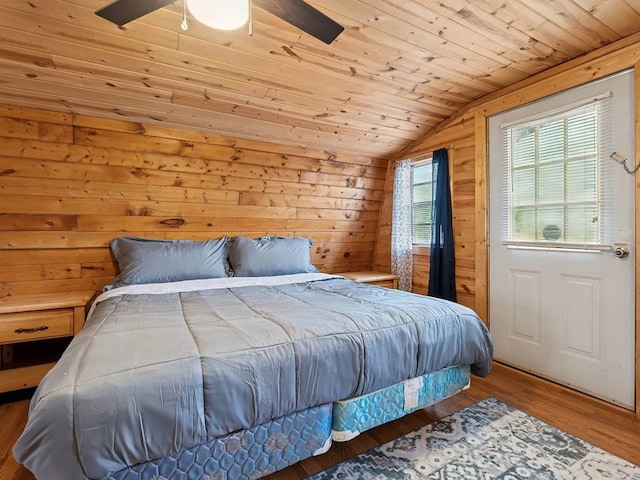 bedroom with wood walls, a ceiling fan, wooden ceiling, wood finished floors, and vaulted ceiling