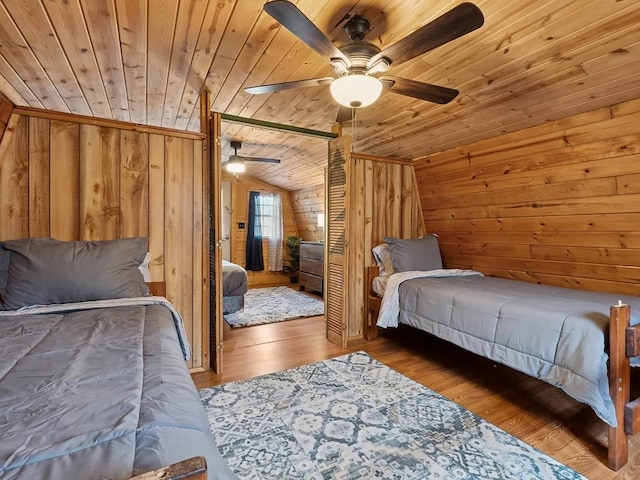 bedroom featuring wood finished floors, ceiling fan, wooden walls, wooden ceiling, and vaulted ceiling