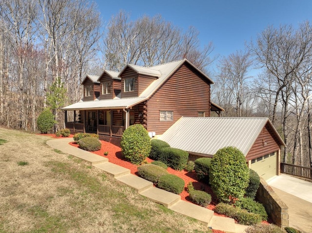 log home with a porch, a front yard, log siding, metal roof, and driveway