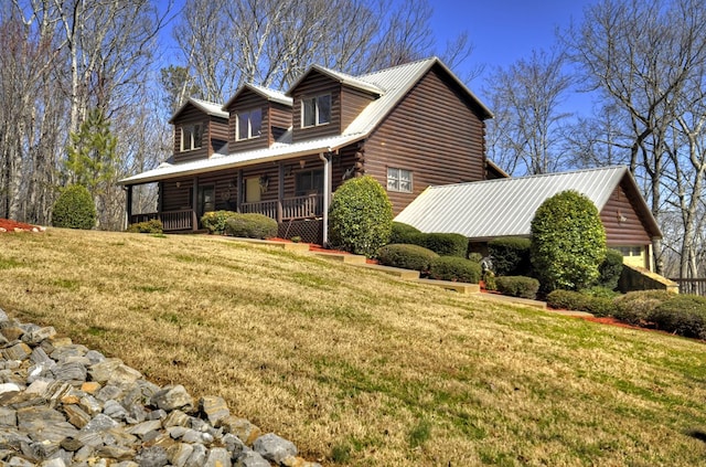 view of property exterior featuring log siding, covered porch, metal roof, and a yard