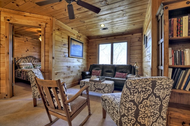 living area with wooden walls, wood ceiling, ceiling fan, and carpet floors