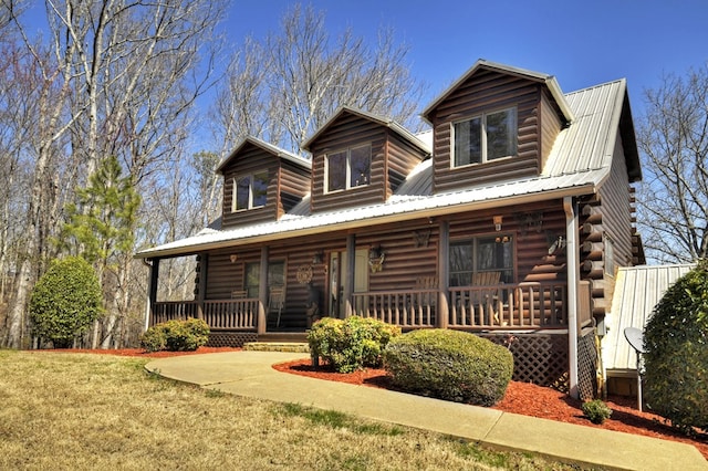 cabin featuring log siding, metal roof, a porch, and a front lawn