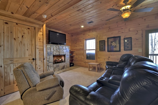 living area featuring wooden walls, a ceiling fan, a fireplace, wood ceiling, and light carpet