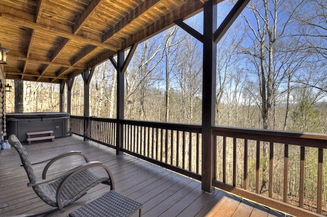 wooden terrace featuring a forest view and a hot tub