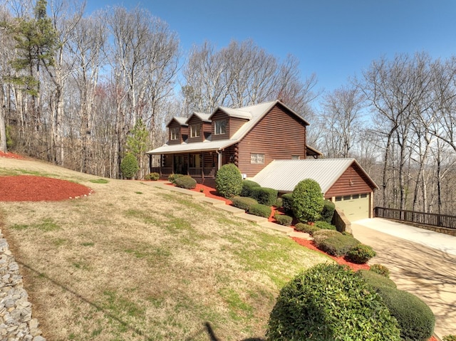 view of home's exterior with a porch, an attached garage, driveway, and a yard