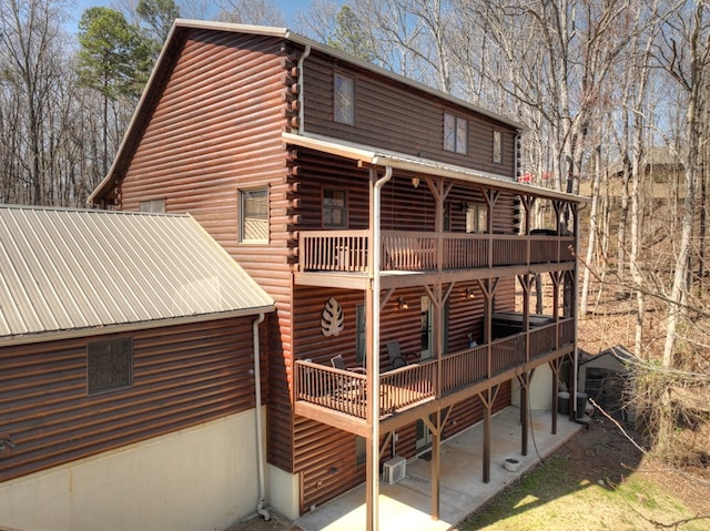 back of property featuring an AC wall unit, central air condition unit, log exterior, and a wooden deck