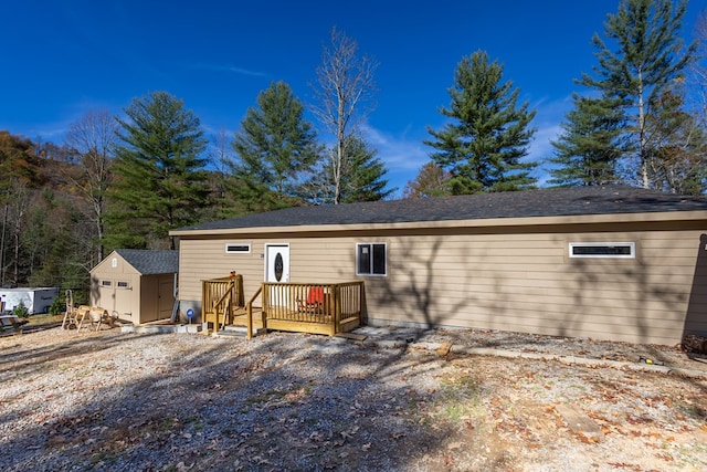 back of house with a deck and a storage unit