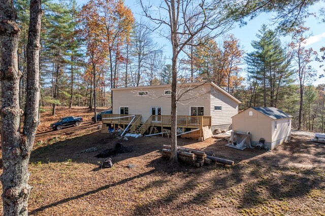 rear view of house with a wooden deck and a storage unit