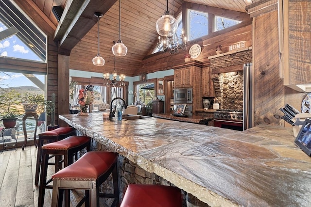 bar featuring stainless steel appliances, a wealth of natural light, hanging light fixtures, an inviting chandelier, and a sink