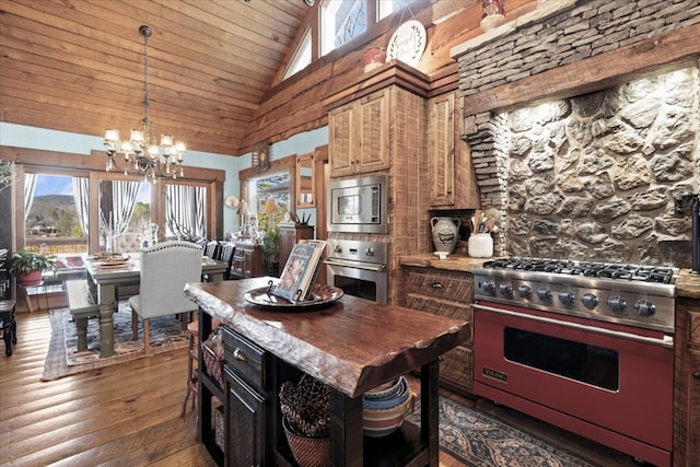 kitchen with high vaulted ceiling, stainless steel appliances, dark wood-type flooring, a kitchen island, and a chandelier