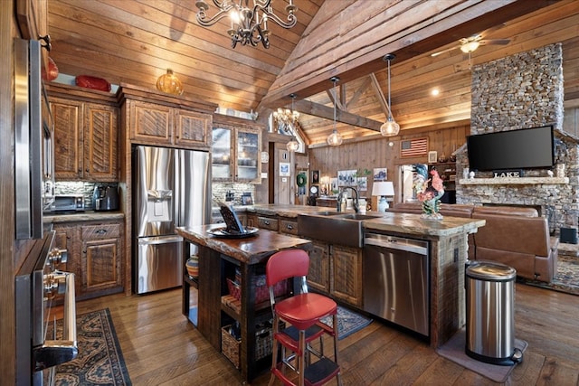 kitchen featuring a center island with sink, glass insert cabinets, a sink, stainless steel appliances, and a notable chandelier