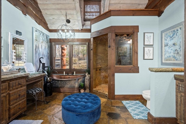 full bathroom with a garden tub, toilet, a notable chandelier, baseboards, and stone finish flooring