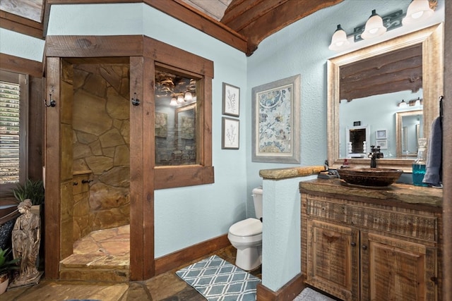 bathroom featuring baseboards, vanity, toilet, and a walk in shower