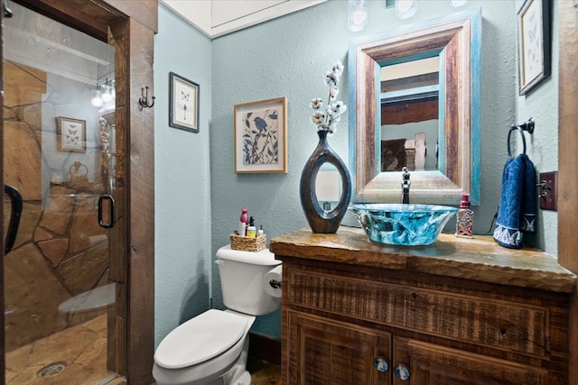 full bathroom featuring toilet, a textured wall, a shower stall, and vanity