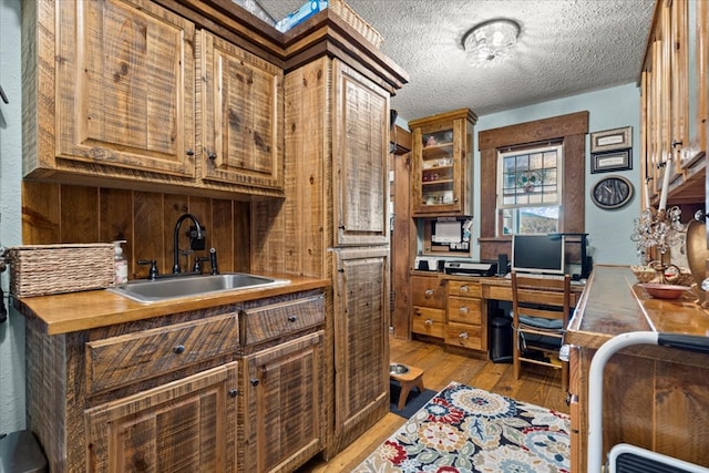 office space featuring light wood-style flooring, a textured ceiling, and a sink