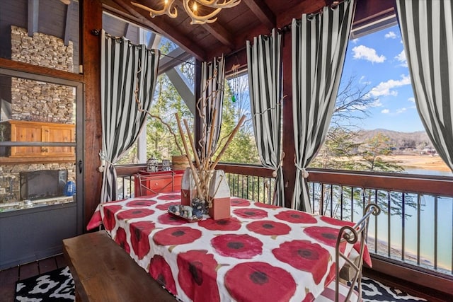 sunroom / solarium featuring lofted ceiling with beams, wood ceiling, and a water and mountain view